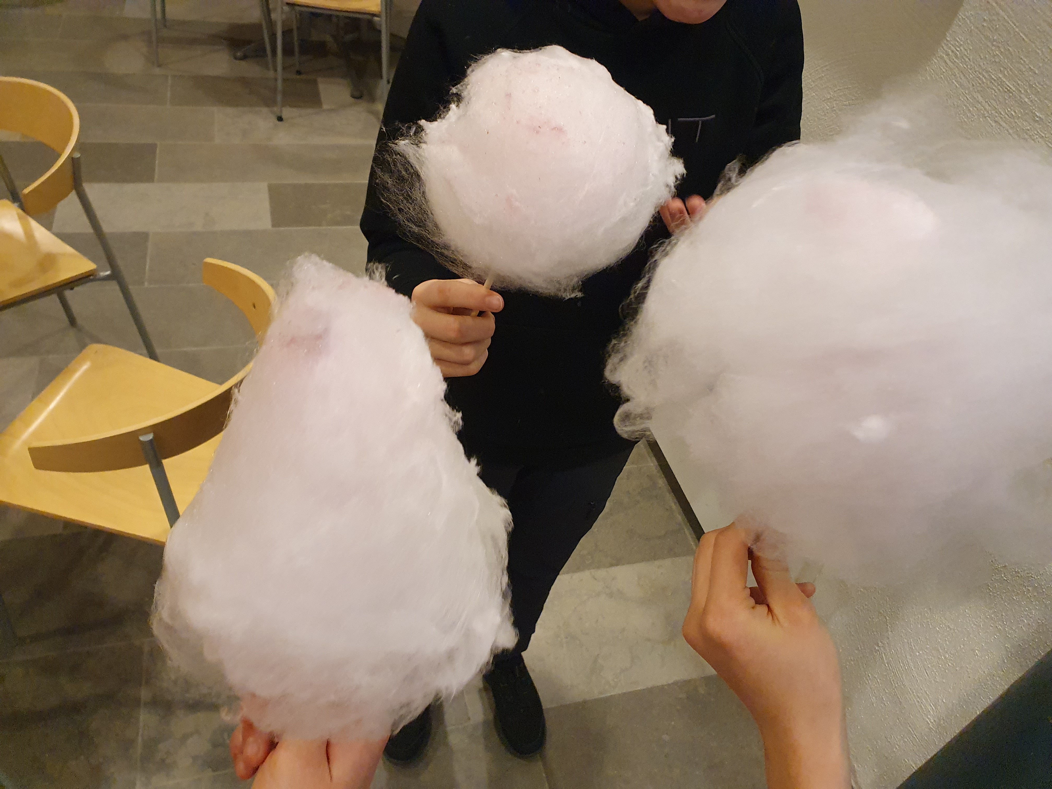 Tre hender held kvar sin rosa sukkerspinn