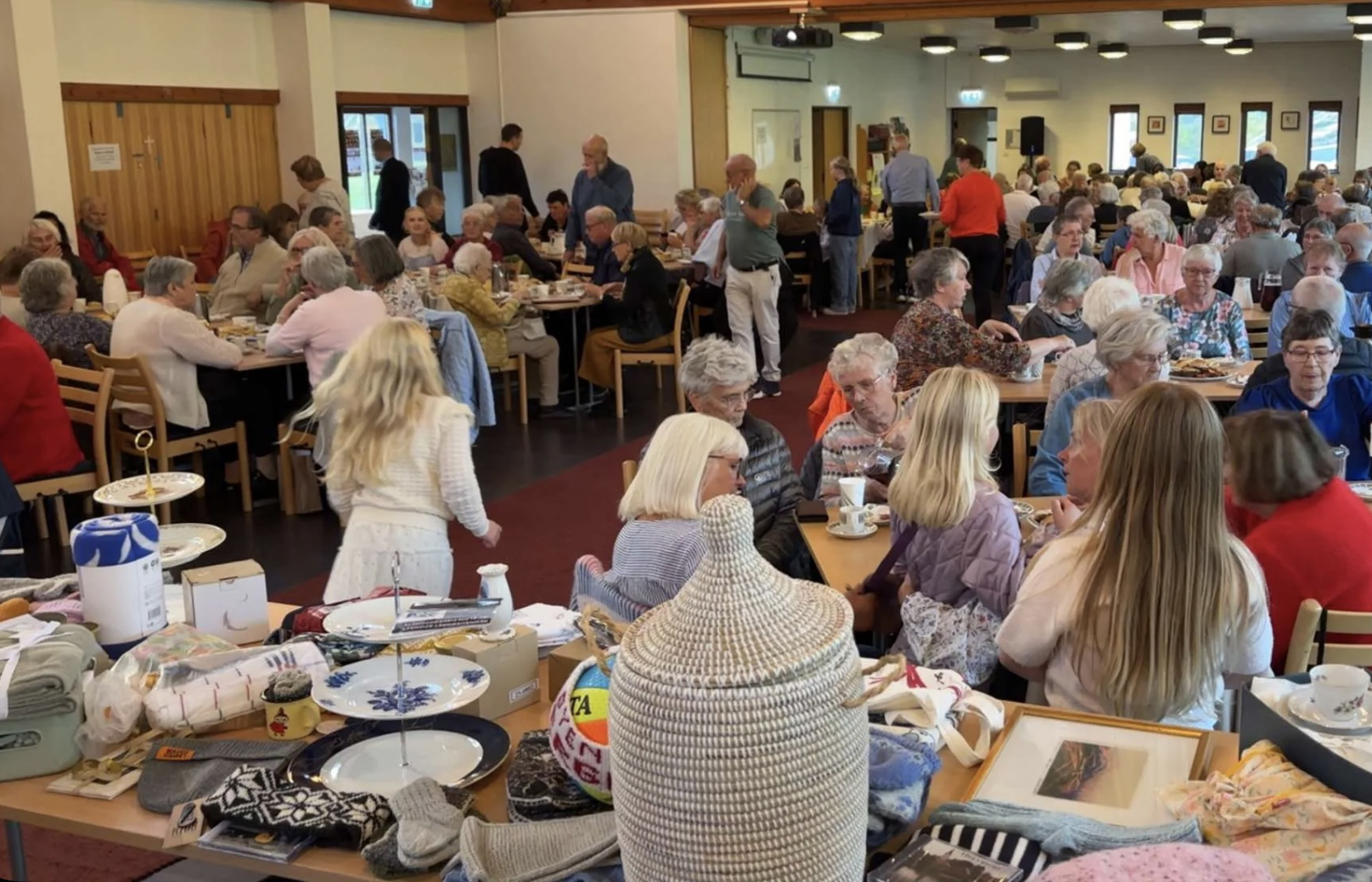 Mennesker sitter rundt bord i en helt full kirke