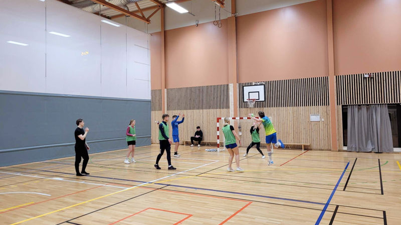 Ungdommer spiller håndball inne i en arena
