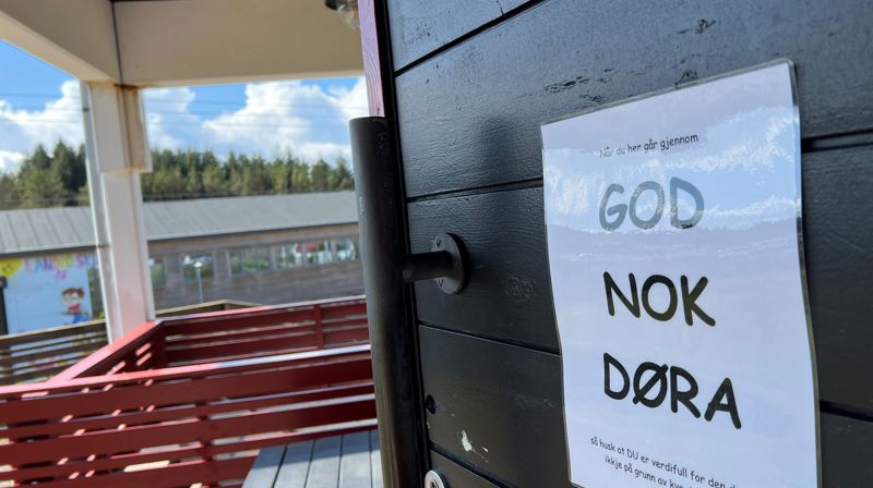 En hvit plakat henger ute på en dør på baksiden av Landro med teksten God nok døra