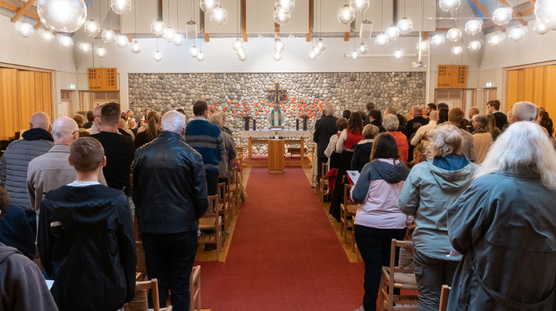 Det er fullsett gudsteneste i Landro kyrkje, vi ser opp midtgangen. Sokneprest Bjarte Nese står bak alteret