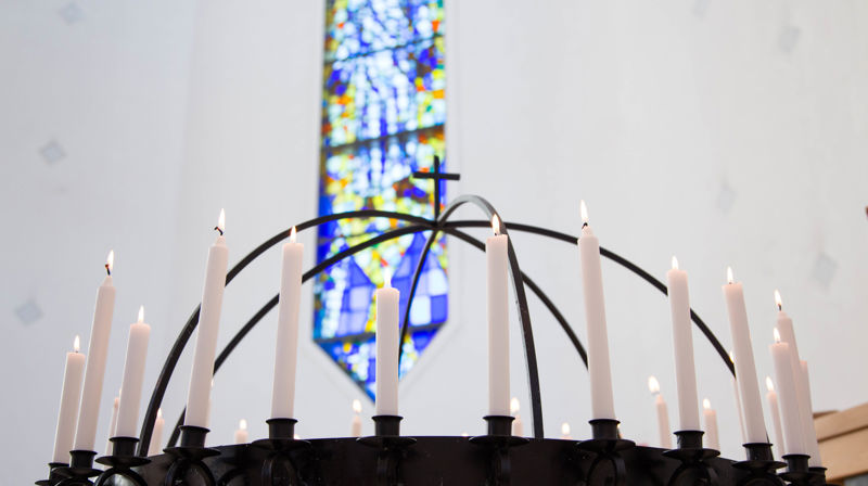 Lysgloben i SUnd kyrkje med tente lys, i bakgrunnen kan ein sjå glassmaleriet