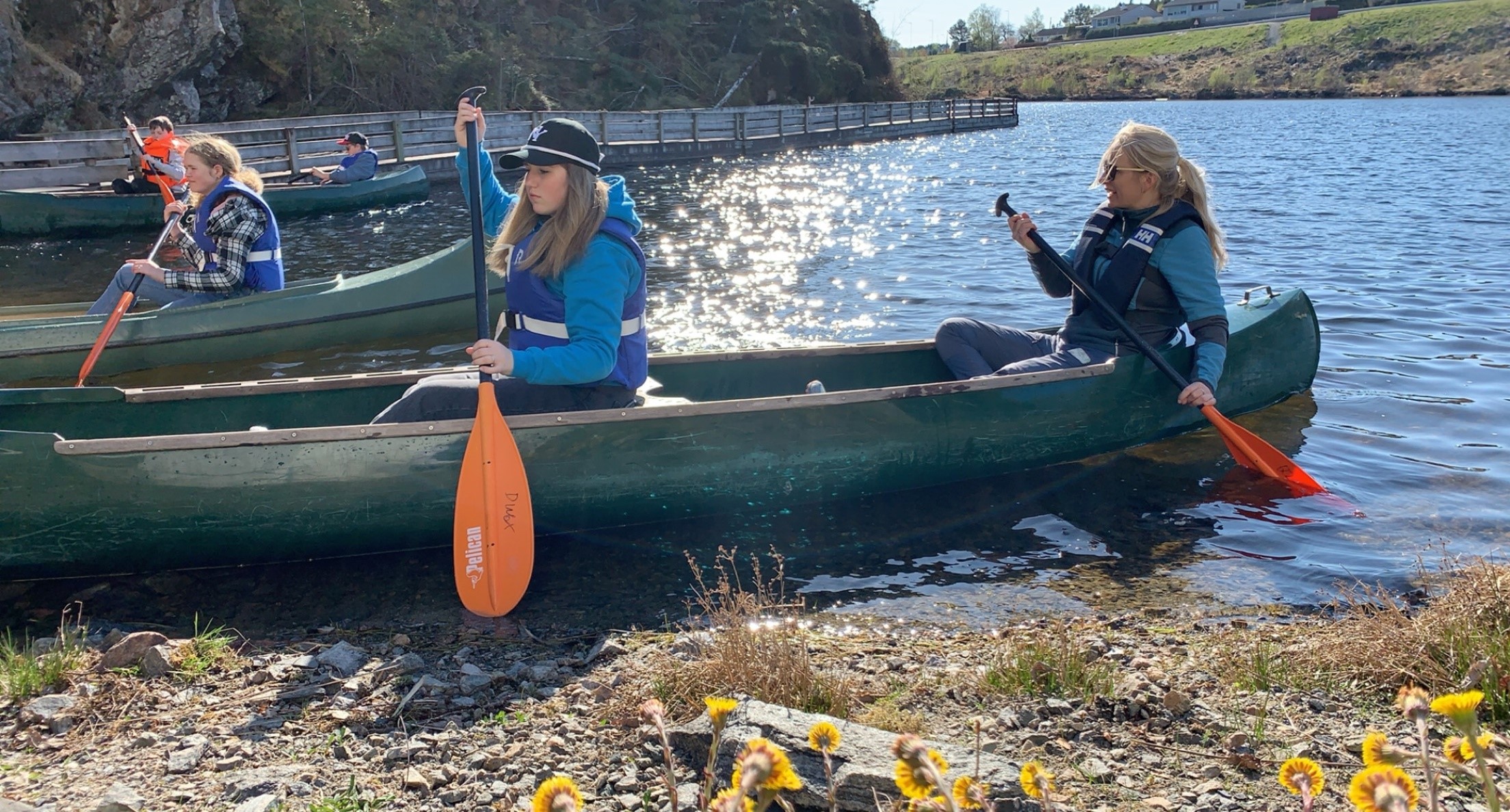 To i kano, på vei inn mot land, det er sol og vår