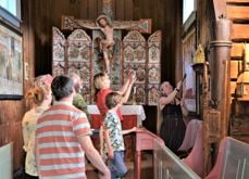 Omviser Marie Veimodet inne i Hedalen stavkirke med en gruppe turister, Foto Linn-Helene Larsen