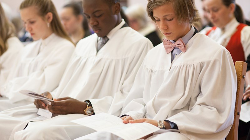 Konfirmanter som sitter på rekke under konfirmasjon. 