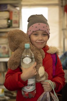 Bildet viser Sofia. Hun flyktet med mor og to søsken fra Cherkassy da flyalarmene gikk ustanselig. De er kommet til vår partner Polish Humanitarian Action og får vann og mat i det varme teltet