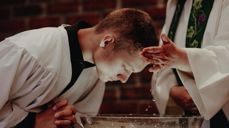 Ung mann døpes i hvit kappe i DNK.  Foto Malin