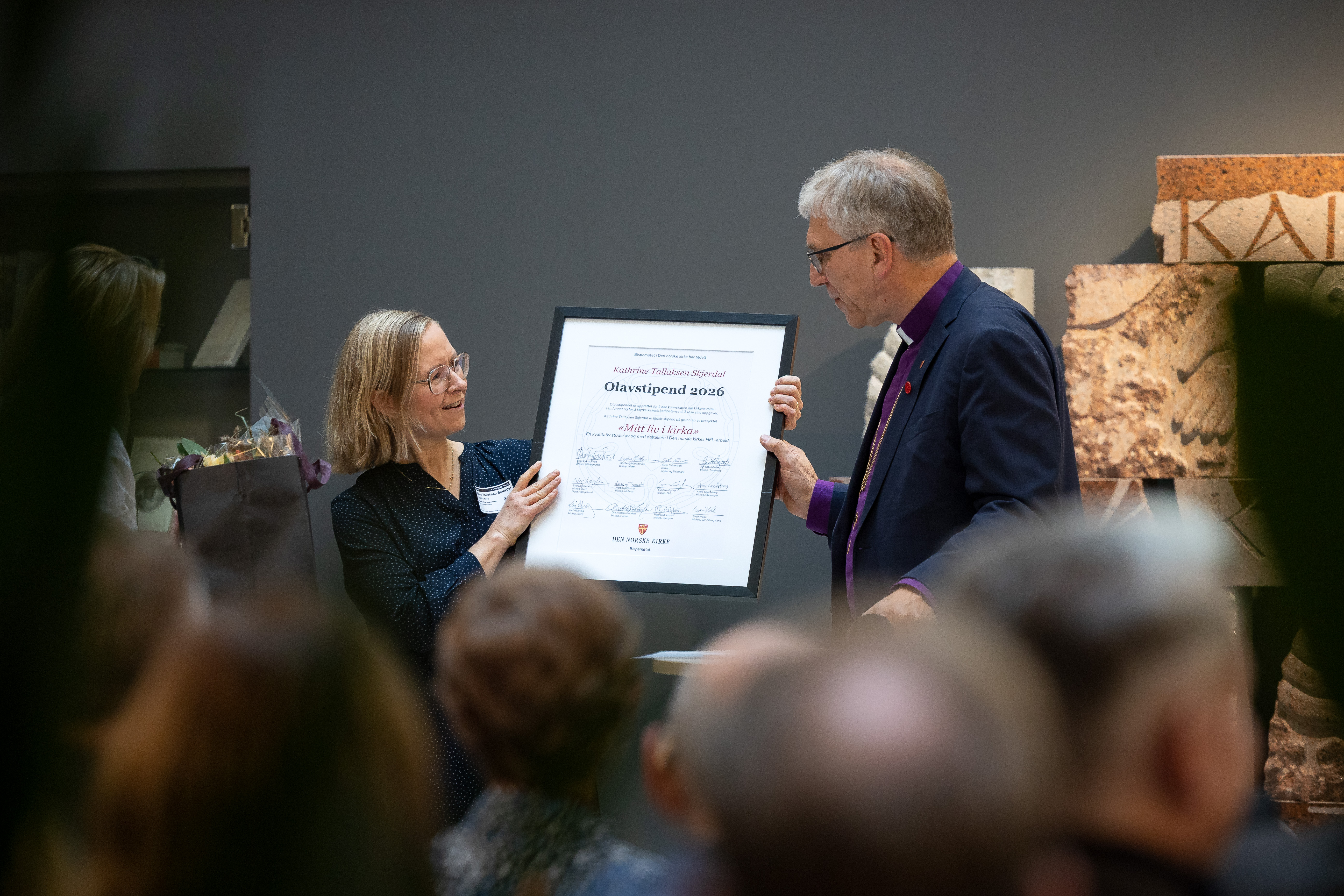 Katrine Tallaksen Skjerdal får stipendet overlevert av preses Olav Fykse Tveit i Kirkens hus. (Foto: Den norske kirke)