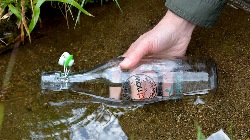 Flasken fylles med vann fra Sunnivaskilden.