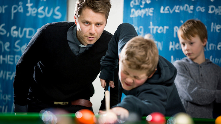 Diakon Arild Tjørve i Vågsbygd kirke spiller biljard med noen ungdommer.