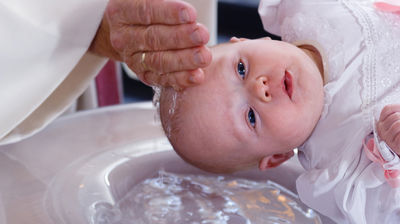 Nærbilde av et dåpsbarn som blir døpt.