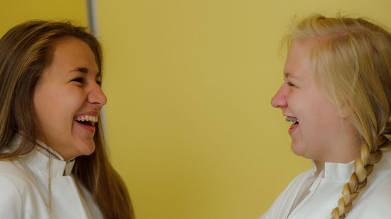 To konfirmanter ser på hverandre og ler.