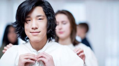 Konfirmant tar på konfirmantkappe.